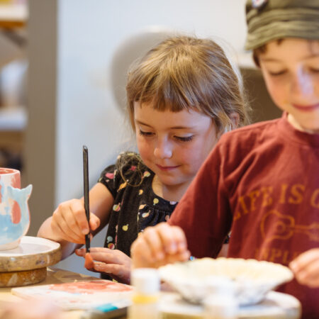 Two children painting pottery at Petroglyph Roseville, CA.